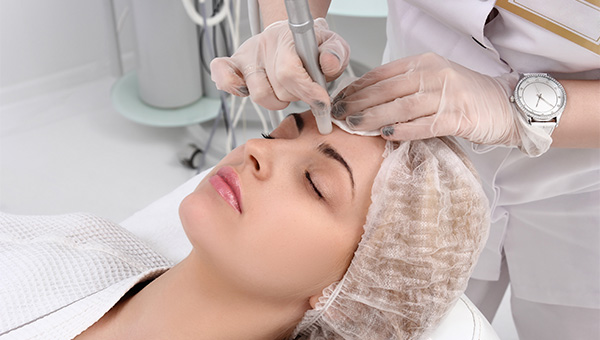 A dermatologist performs a procedure on the forehead of a female patient.