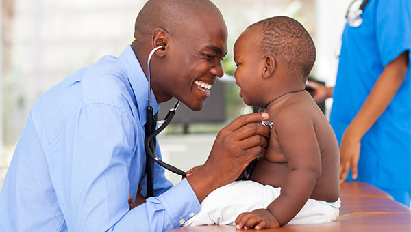 A male doctor using a stethoscope to check the vital signs of a little boy