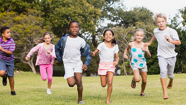 A group of boys and girls is running in a park.
