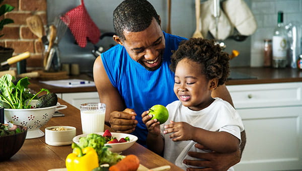 A father and his young daughter eating a healthy meal together.