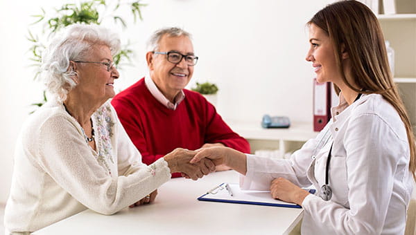 A female nurse meets with a senior couple.