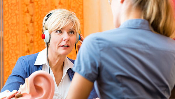 A senior woman is wearing a headset and getting a hearing test.