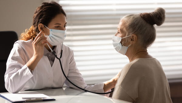 a physician holding a stethoscope to a womans chest