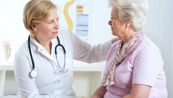 A female doctor talking to an elderly, female patient. 
