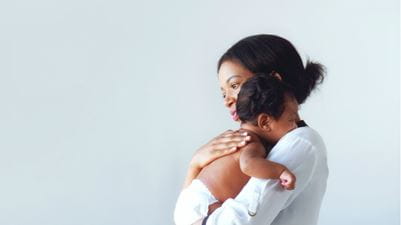 Mother holding her baby on grey background