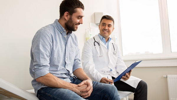 A male doctor is talking with a male patient during an office visit.