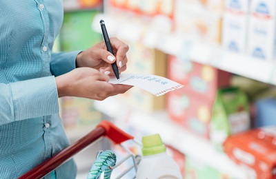 A woman is checking her list while shopping at the grocery store.