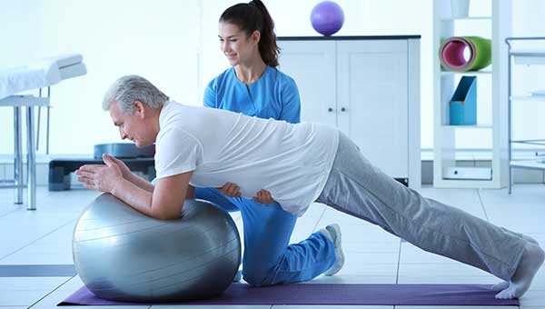 A physical therapist is helping a male patient with rehabilitation exercises.