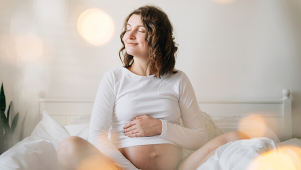 Pregnant lady smiling while touching her belly