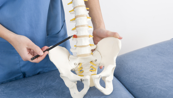 A doctor points to a herniated disc on a model of a spine.