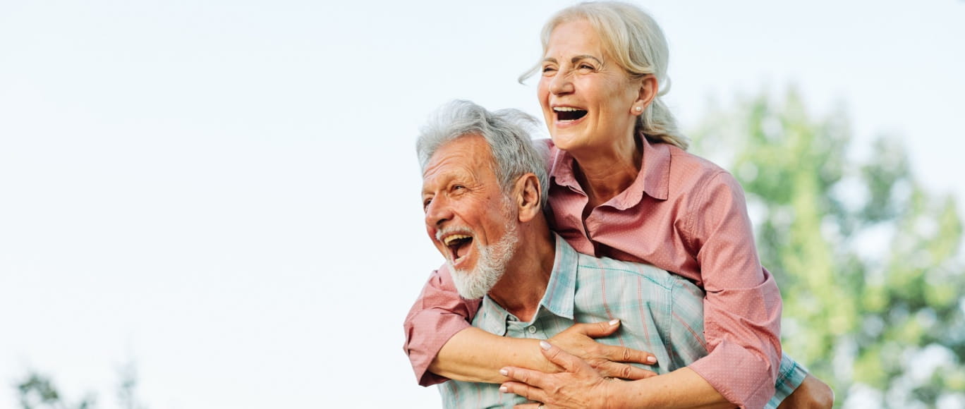 Grandpa piggy backing grandma, smiling and laughing