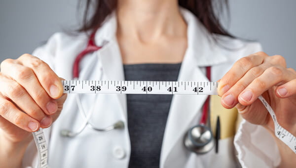 Female doctor holding a tape measurer. 