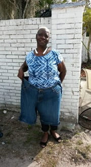 Synovia standing with both legs inside one pant leg of her old jeans