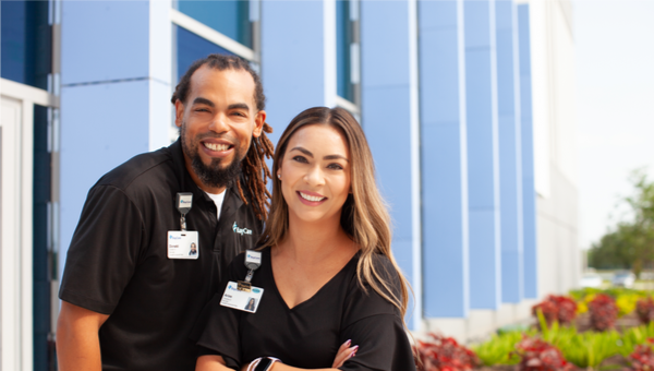 A male and female BayCare employee standing together outside smiling.