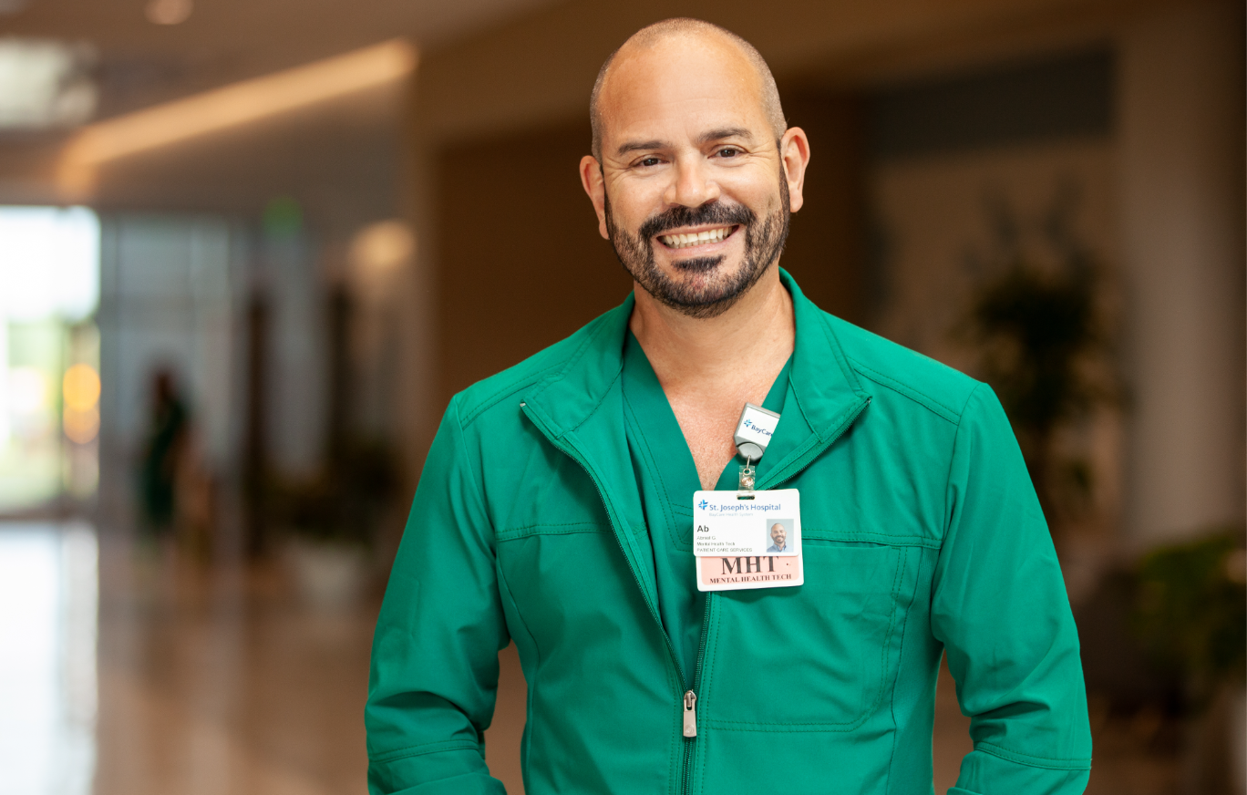 Male employee at BayCare smiling with a badge on. 