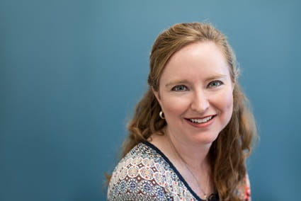 Young woman smiling in front of a dark blue background