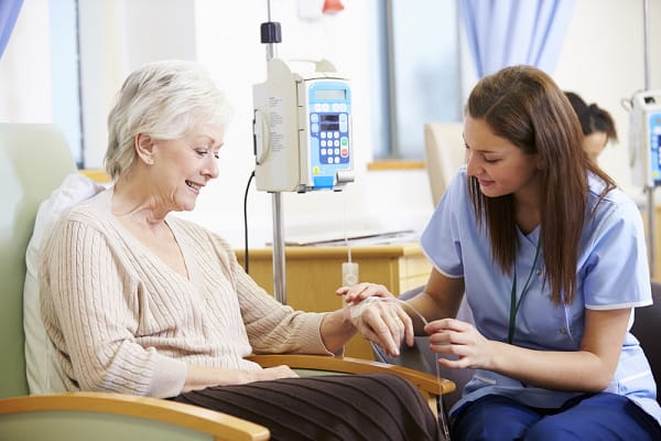 young woman nursing professional helping elderly patient with iv