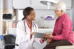 A female doctor talks with a senior female patient.