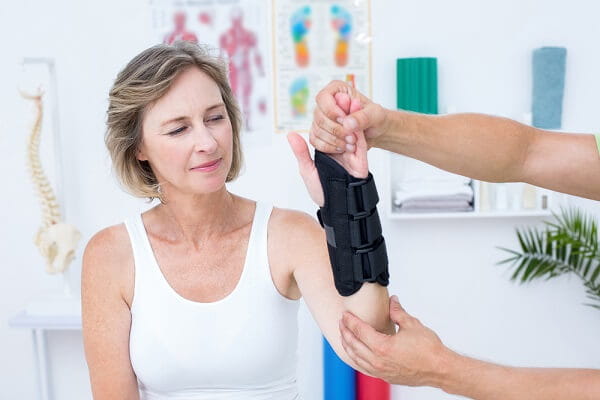 Doctor examining his patients wrist in medical office