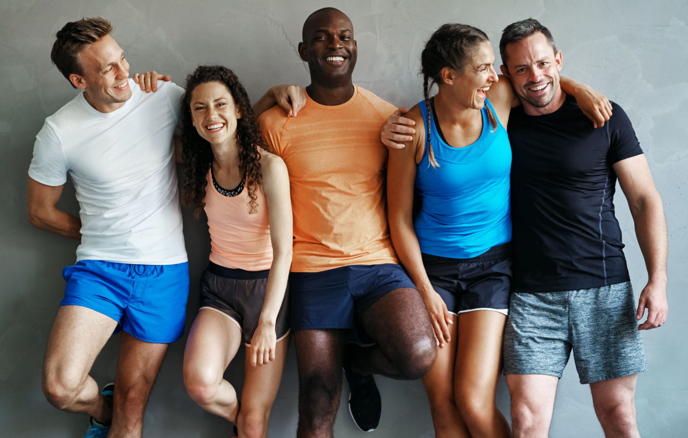 Group of active adults standing and smiling.