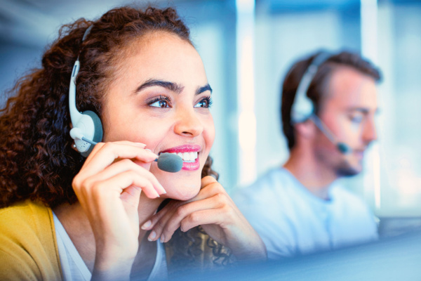 a woman in a call center wearing a headset assisting customers with a smile
