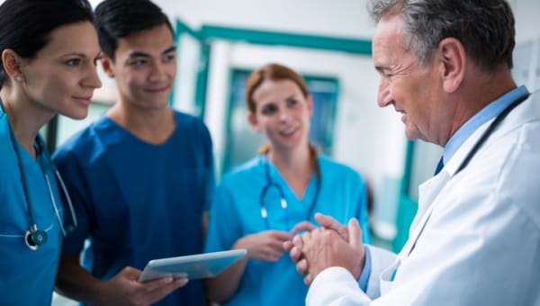 A team of doctors huddled together coordinating efforts while smiling