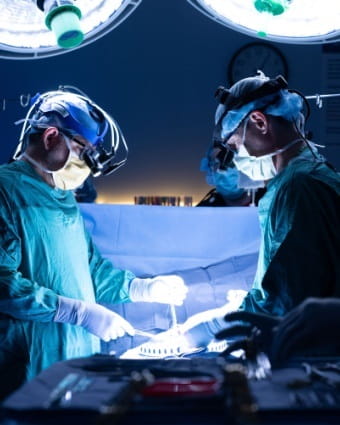 Two doctors perform open-heart surgery around an operating table.