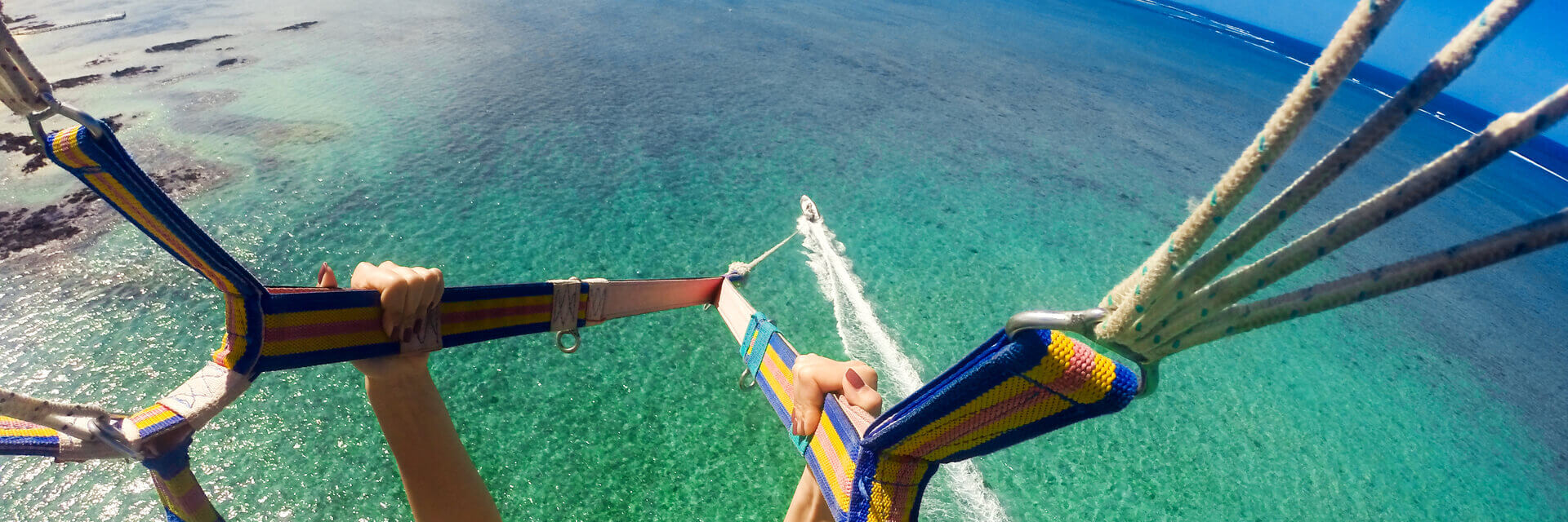 person parasailing high above water and the boat pulling them