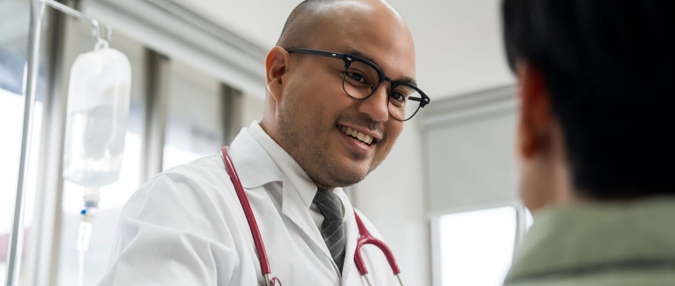 A male cardiologist smiles warmly at a patient during a consultation in a medical office.