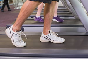 A senior male walks on a treadmill.