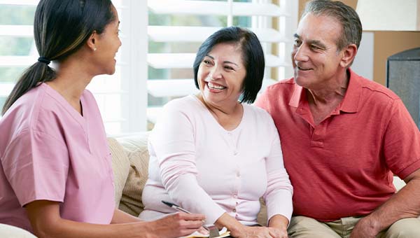 A home health provider talks with a couple in their home.