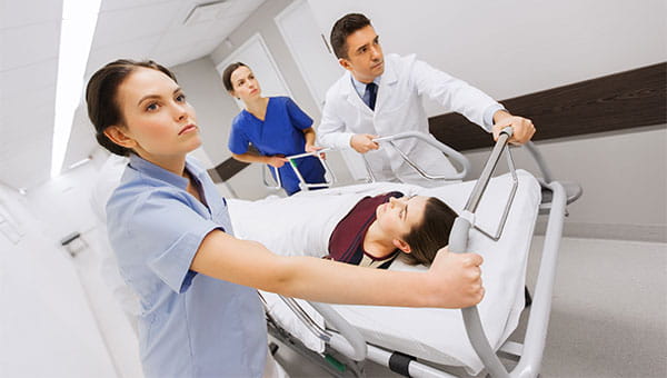 A team of doctors and nurses pushes a patient on a hospital bed.