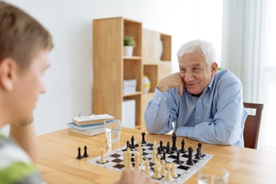 A grandfather plays chess with his grandson.