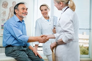 A senior male patient talking with a female doctor.