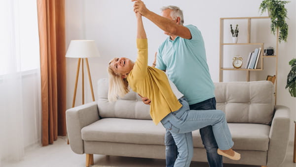 Senior couple dancing in the living room in front of the couch