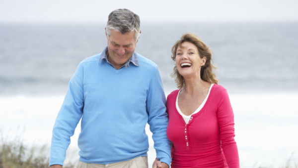 Man and woman walking together happily on the beach.