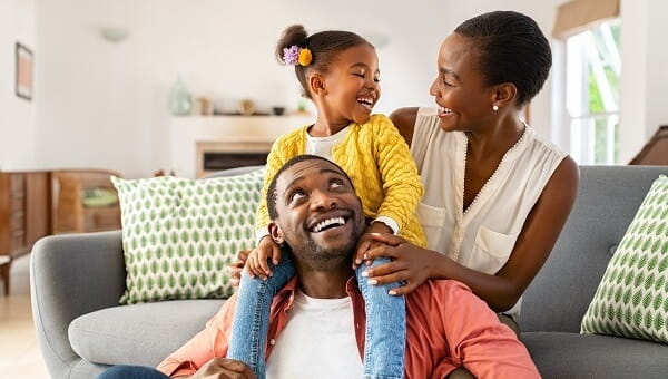 a mother father and daughter laughing in their living room