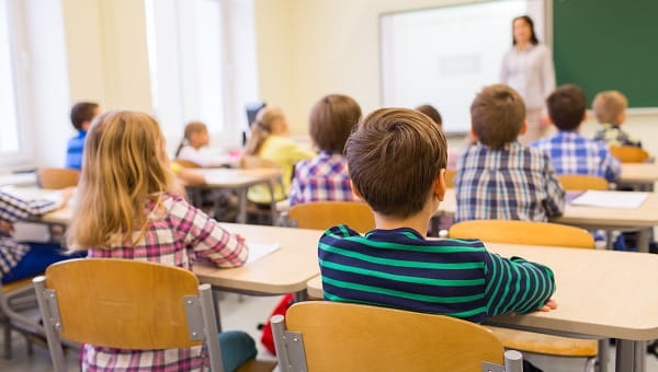Children are sitting in a classroom and listening to their teacher.