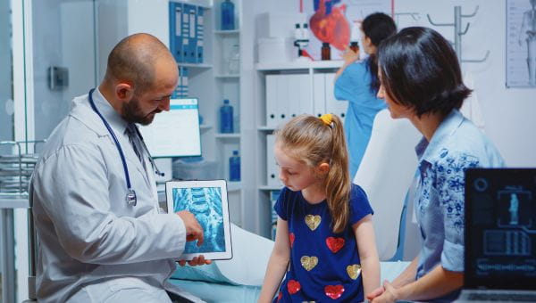 male doctor reviewing x-ray with child and parent
