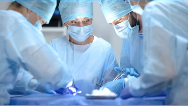 A group of four doctors practicing surgery on a patient 