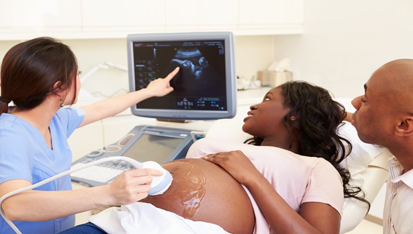 A doctor is performing an ultrasound on a mother as the mother and father look at the monitor