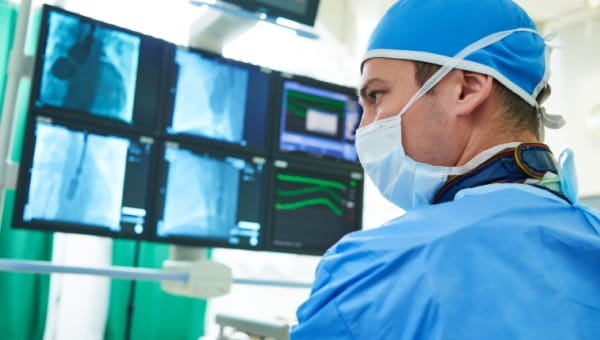 A doctor looking at a computer while performing surgery