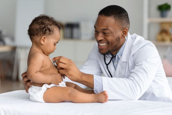 A smiling doctor examining a baby