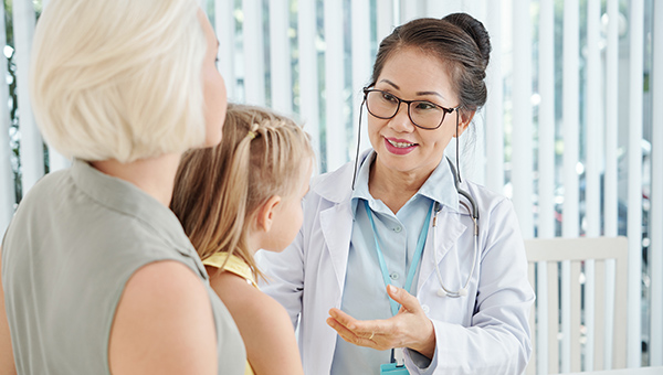 A doctor talking to the mother of a pediatric patient at a doctor's office