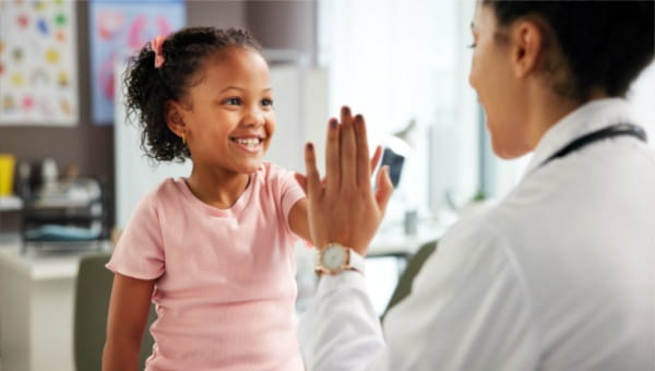 A pediatric patient high fiving their primary care provider