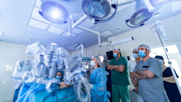 a group of doctors and healthcare workers using a robotic assisted surgery machine