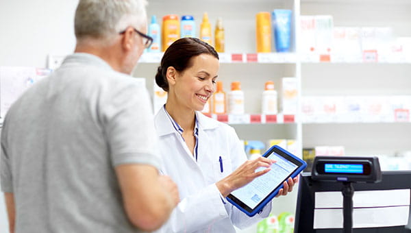 Pharmacist looking at a tablet and sharing information with a customer