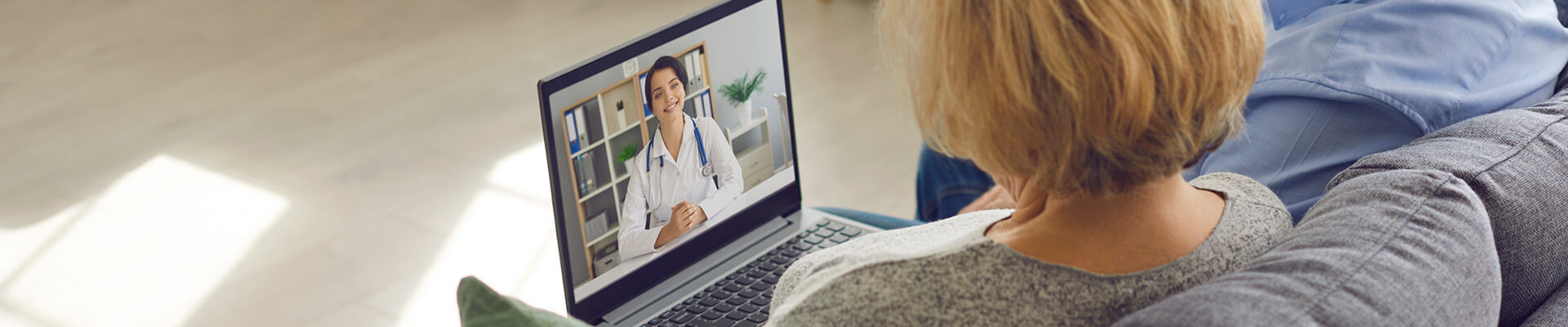 woman in video call with female physician wearing labcoat on laptop screen