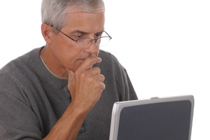 A middle age man in deep concentration reads on a laptop