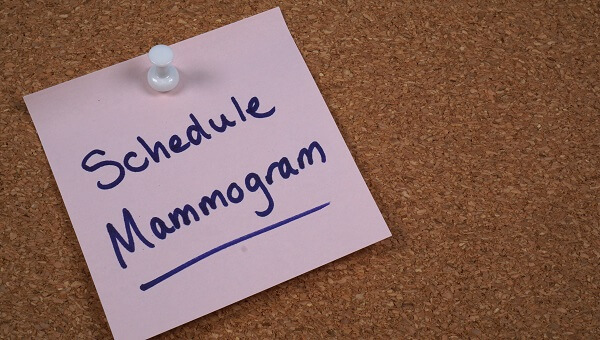 a pink note on a corkboard that reads schedule mammogram